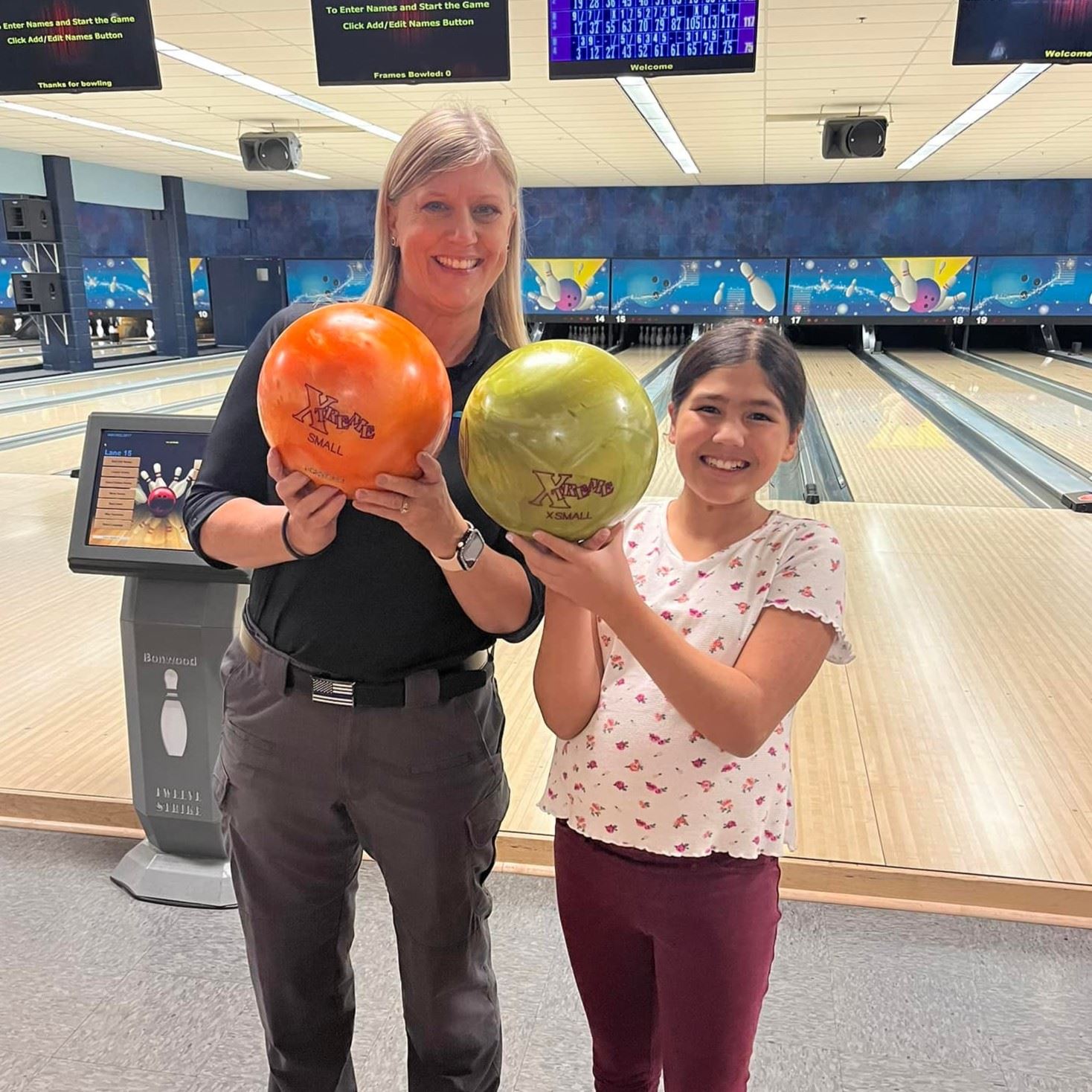 police officer and girl standing next to each other holding bowling balls